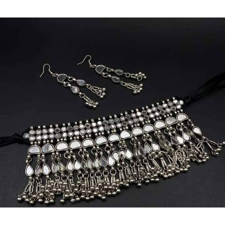 Premium qualityRecreating the opulence of Indian beauty in this beautiful necklace set. Our Silver Oxidised Necklace set is a head-turner with lovely traditional aesthetics that makes its way to a must-have It features intricate floral designs with pearl drops, which adds the perfect amount of drama to the look. It comes with matching jhumki earrings , a ring, pair of bangles, and a nose pin that will complete your look. This necklace set will be the perfect add on to your occasion-specific dre