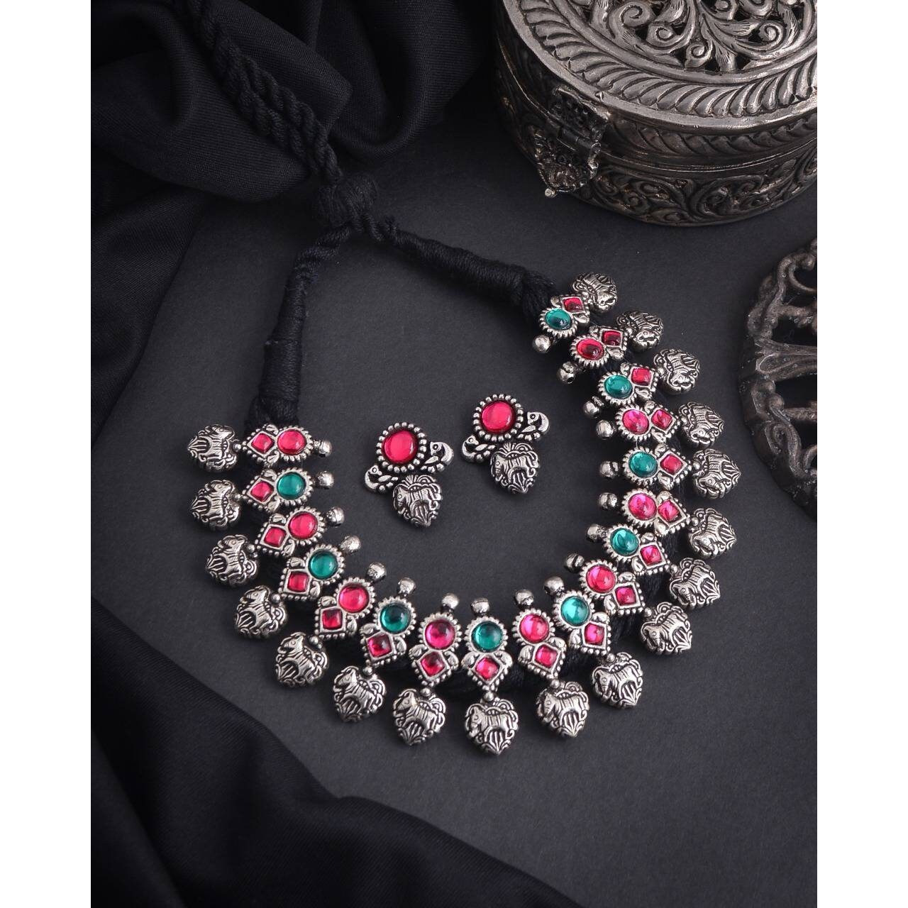 This minimalistic long oxidized necklace set is perfect for an Indian bride. Beautifullydesigned with German oxidized silver and repetitive flower patterns, this wedding set has abig intricate long Haram oxidized necklace with a choker silver necklace, a pair of studearrings, a ring, a pair of bangles, and a nose pin. This bridal oxidized set is available in three different patterns and sizes. Each of these pieces will work wonderfully on its own and even more elegant when worn together. You can
