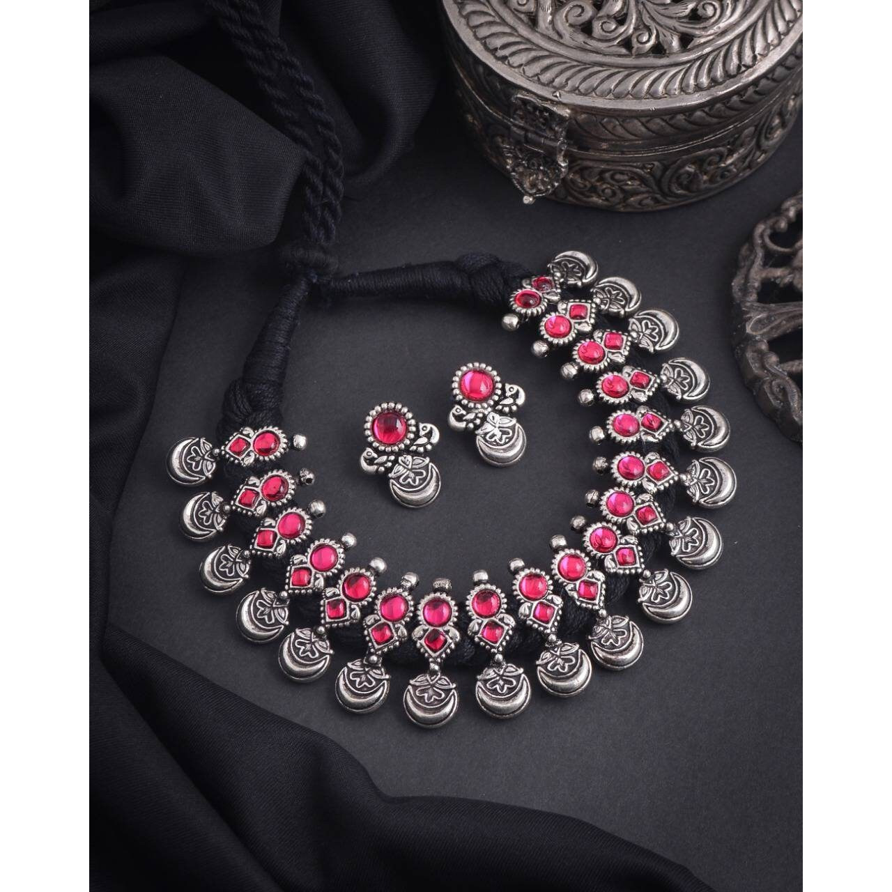 This minimalistic long oxidized necklace set is perfect for an Indian bride. Beautifullydesigned with German oxidized silver and repetitive flower patterns, this wedding set has abig intricate long Haram oxidized necklace with a choker silver necklace, a pair of studearrings, a ring, a pair of bangles, and a nose pin. This bridal oxidized set is available in three different patterns and sizes. Each of these pieces will work wonderfully on its own and even more elegant when worn together. You can