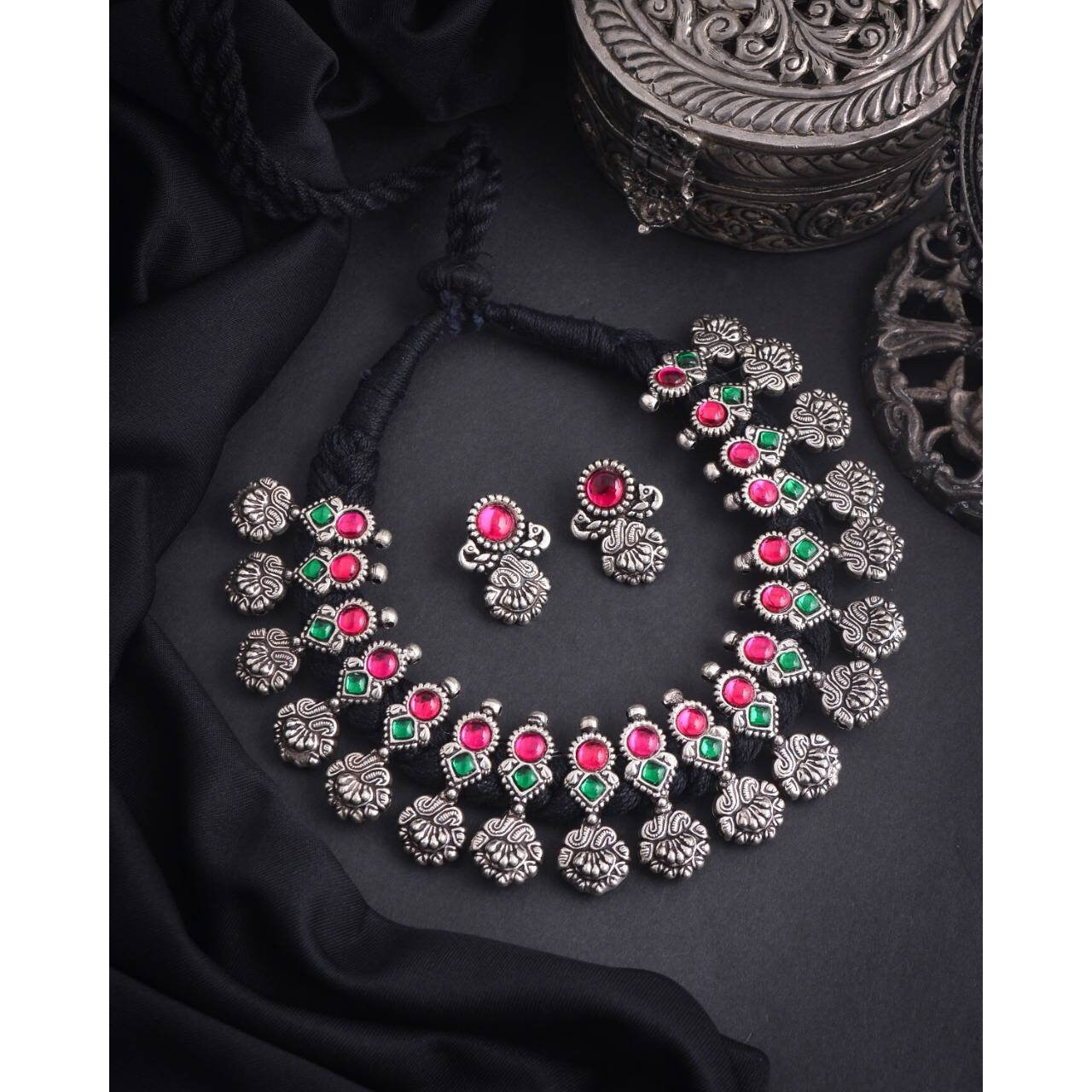This minimalistic long oxidized necklace set is perfect for an Indian bride. Beautifullydesigned with German oxidized silver and repetitive flower patterns, this wedding set has abig intricate long Haram oxidized necklace with a choker silver necklace, a pair of studearrings, a ring, a pair of bangles, and a nose pin. This bridal oxidized set is available in three different patterns and sizes. Each of these pieces will work wonderfully on its own and even more elegant when worn together. You can