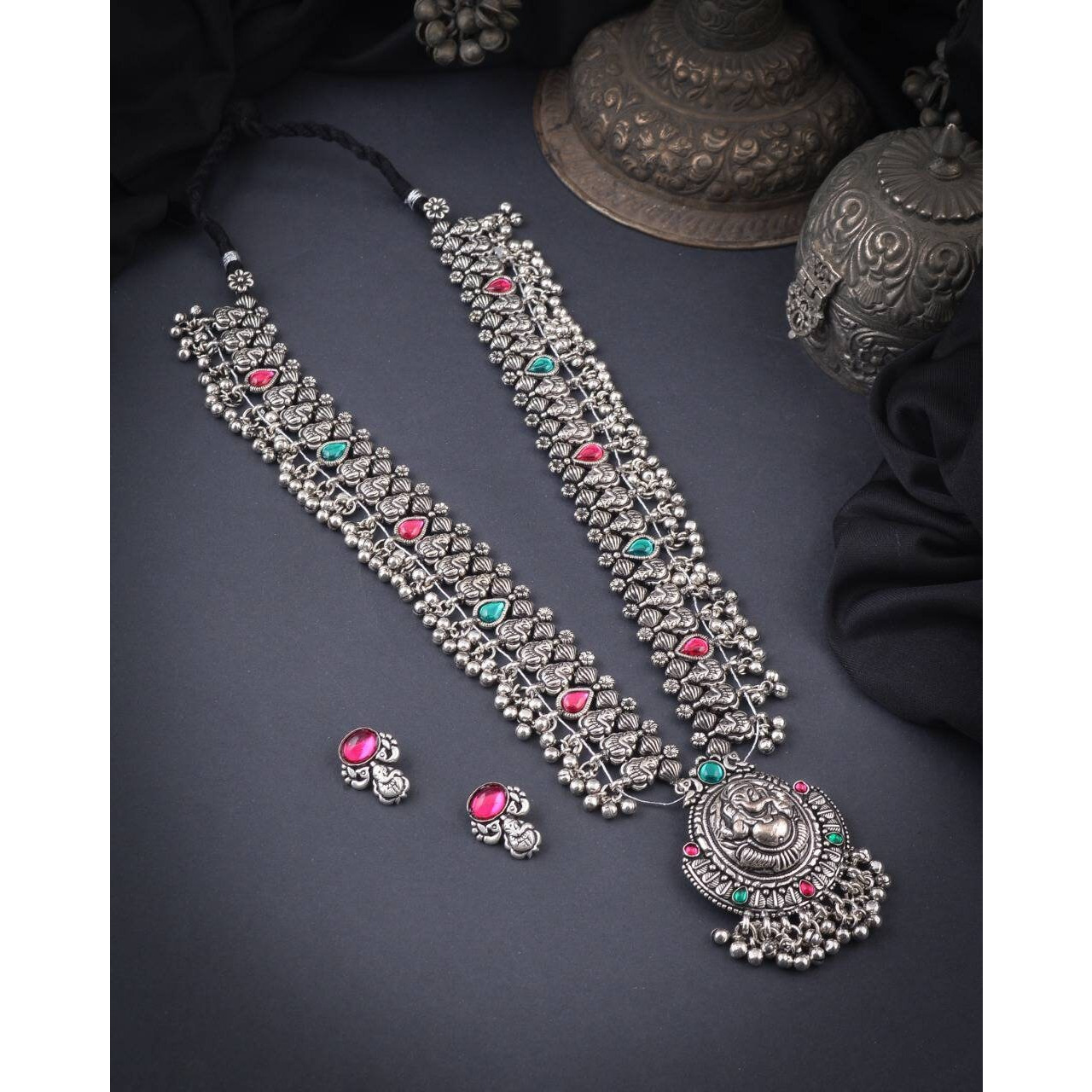 Steal the show with our Indian oxidized German silver long double necklace full combo set.It is a set of 6 beautifully designed pieces of jewellery, having a big long Haram oxidizednecklace, choker silver necklace, a pair of jhumka earrings, ring, a pair of bangles, and nosepin, hand-made with German oxidized silver to give it a dignified look. Style this with yourfavourite ethnics or Indo-western outfits, and you are ready for Navratri This hand-madeKolhapuri boho necklace set may have slight