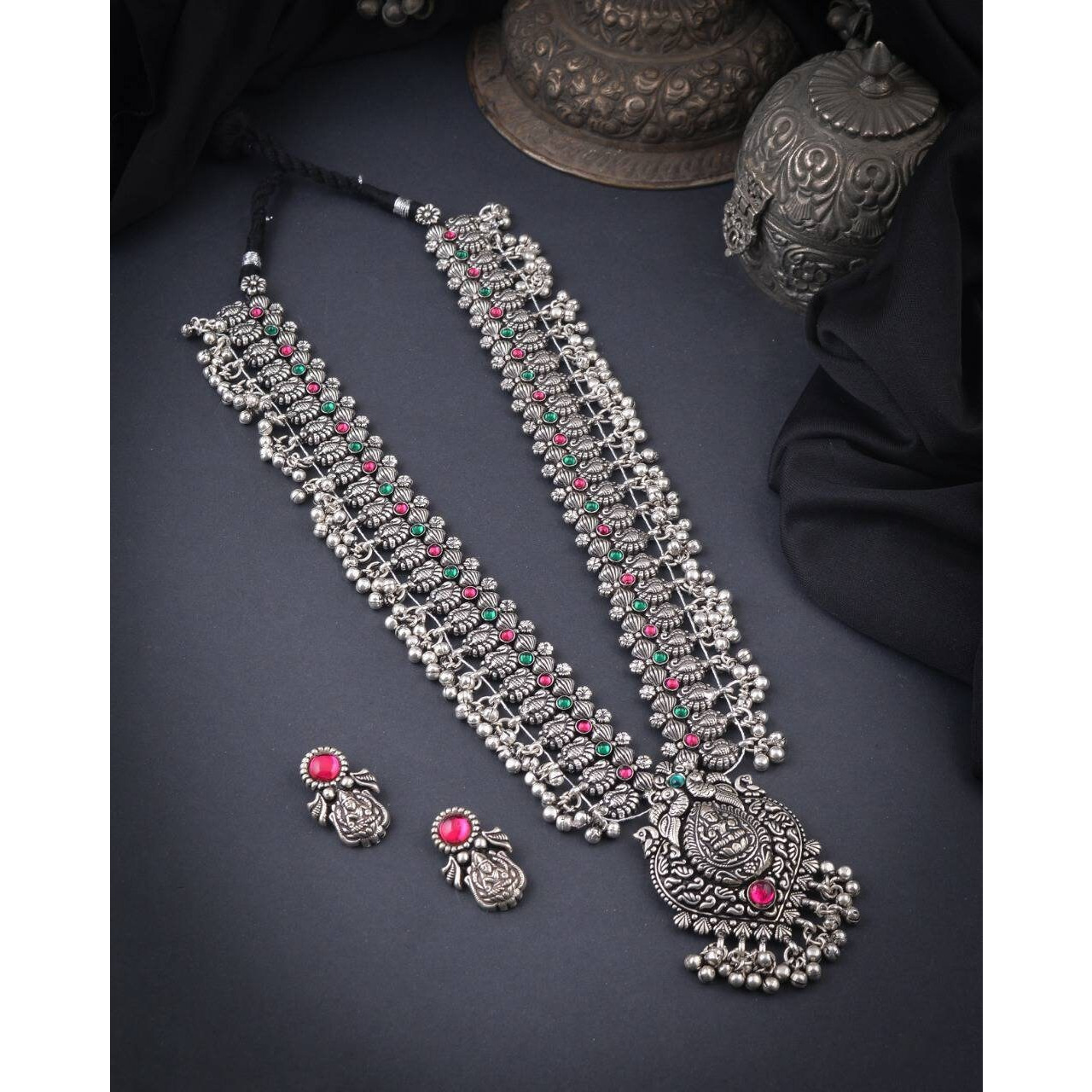 Steal the show with our Indian oxidized German silver long double necklace full combo set.It is a set of 6 beautifully designed pieces of jewellery, having a big long Haram oxidizednecklace, choker silver necklace, a pair of jhumka earrings, ring, a pair of bangles, and nosepin, hand-made with German oxidized silver to give it a dignified look. Style this with yourfavourite ethnics or Indo-western outfits, and you are ready for Navratri This hand-madeKolhapuri boho necklace set may have slight
