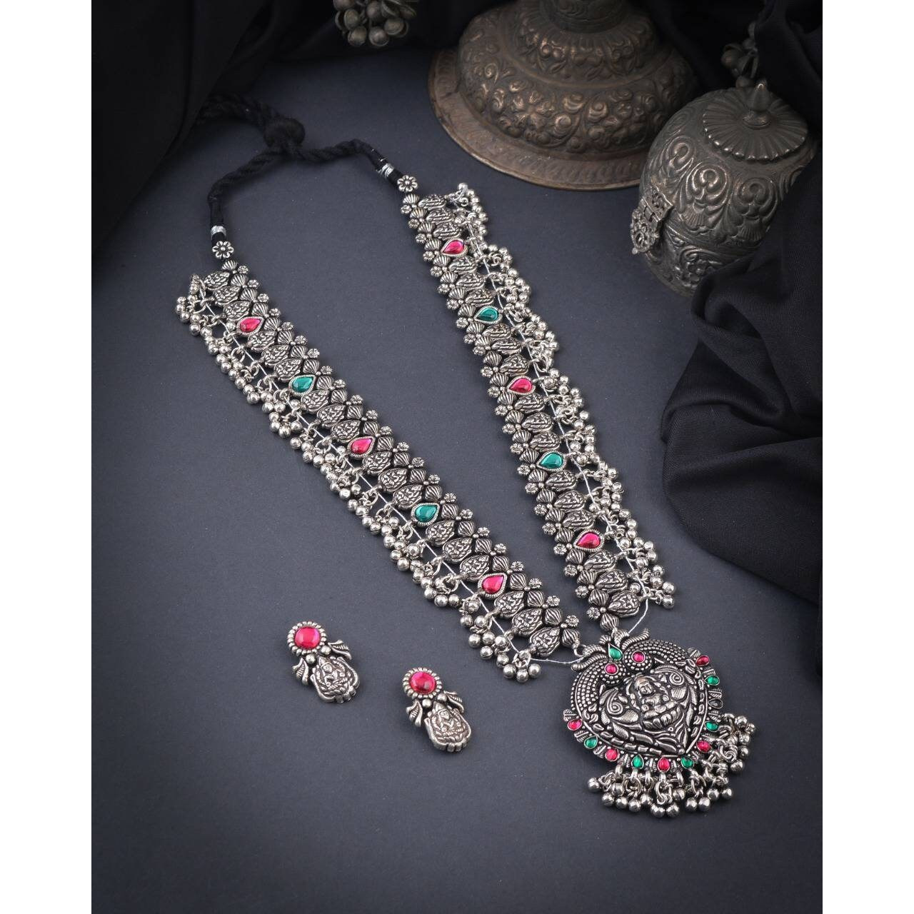 Steal the show with our Indian oxidized German silver long double necklace full combo set.It is a set of 6 beautifully designed pieces of jewellery, having a big long Haram oxidizednecklace, choker silver necklace, a pair of jhumka earrings, ring, a pair of bangles, and nosepin, hand-made with German oxidized silver to give it a dignified look. Style this with yourfavourite ethnics or Indo-western outfits, and you are ready for Navratri This hand-madeKolhapuri boho necklace set may have slight
