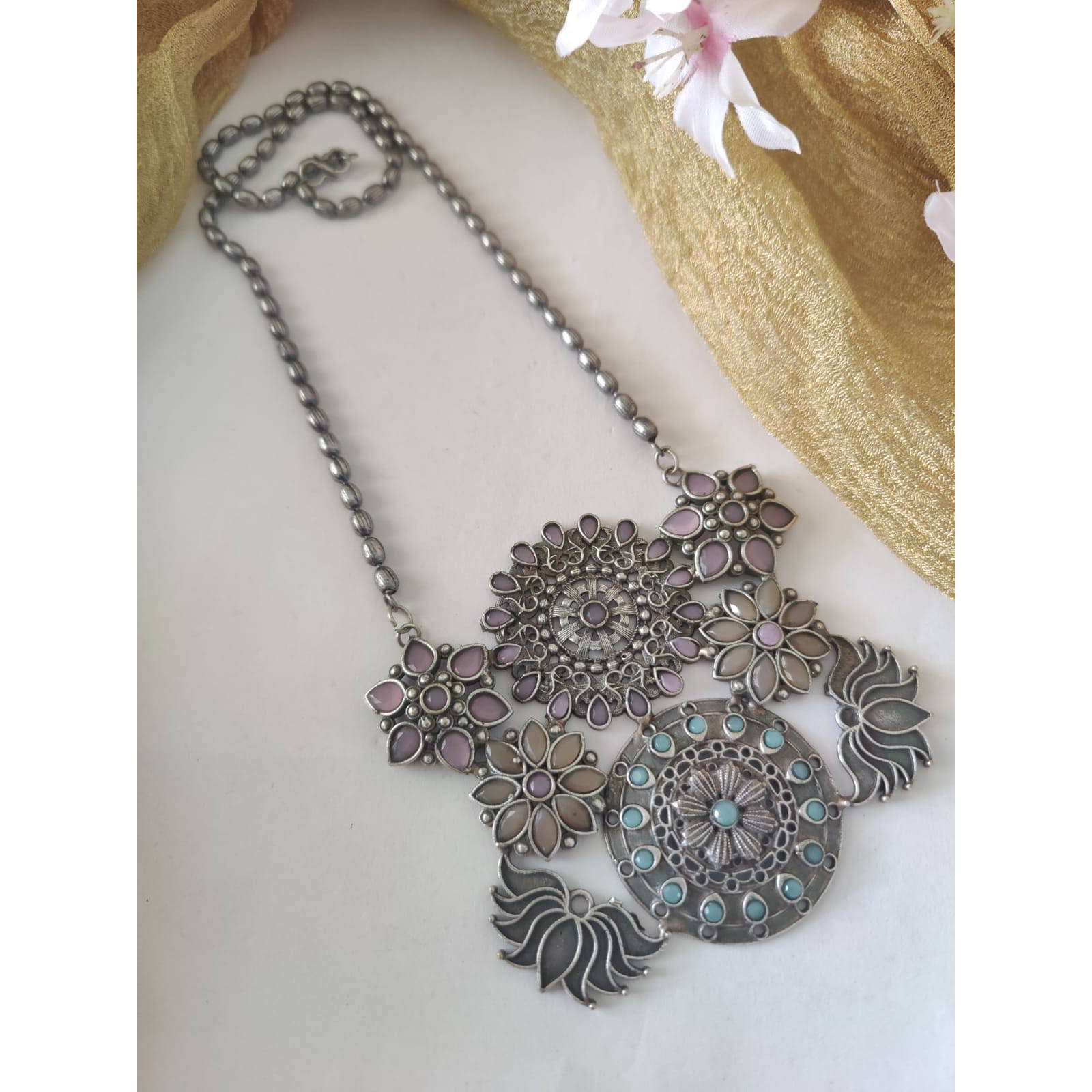 Are you a big fan of boho and tribal-inspired oxidized jewelry Then this set can be your match made in heaven. Studded with beautiful little tribal-themed mirrors and adorned with cute little ghungroos, this set of Indian oxidized jewelry comprises an elegant necklace and a pair of matching earrings. The jewelry comes with an extra plating of silver for longer sustainability. It can be a great gift for your loved ones. You need to ensure that you store it in an airtight place, away from moistur