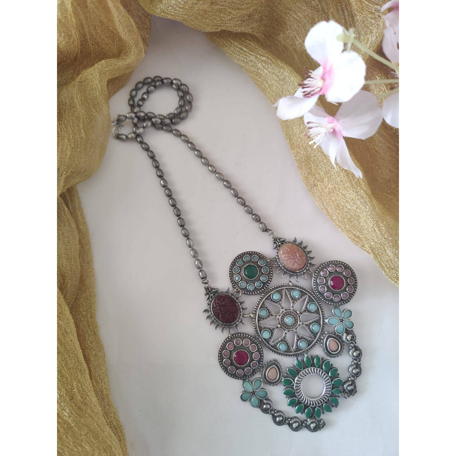 Are you a big fan of boho and tribal-inspired oxidized jewelry Then this set can be your match made in heaven. Studded with beautiful little tribal-themed mirrors and adorned with cute little ghungroos, this set of Indian oxidized jewelry comprises an elegant necklace and a pair of matching earrings. The jewelry comes with an extra plating of silver for longer sustainability. It can be a great gift for your loved ones. You need to ensure that you store it in an airtight place, away from moistur