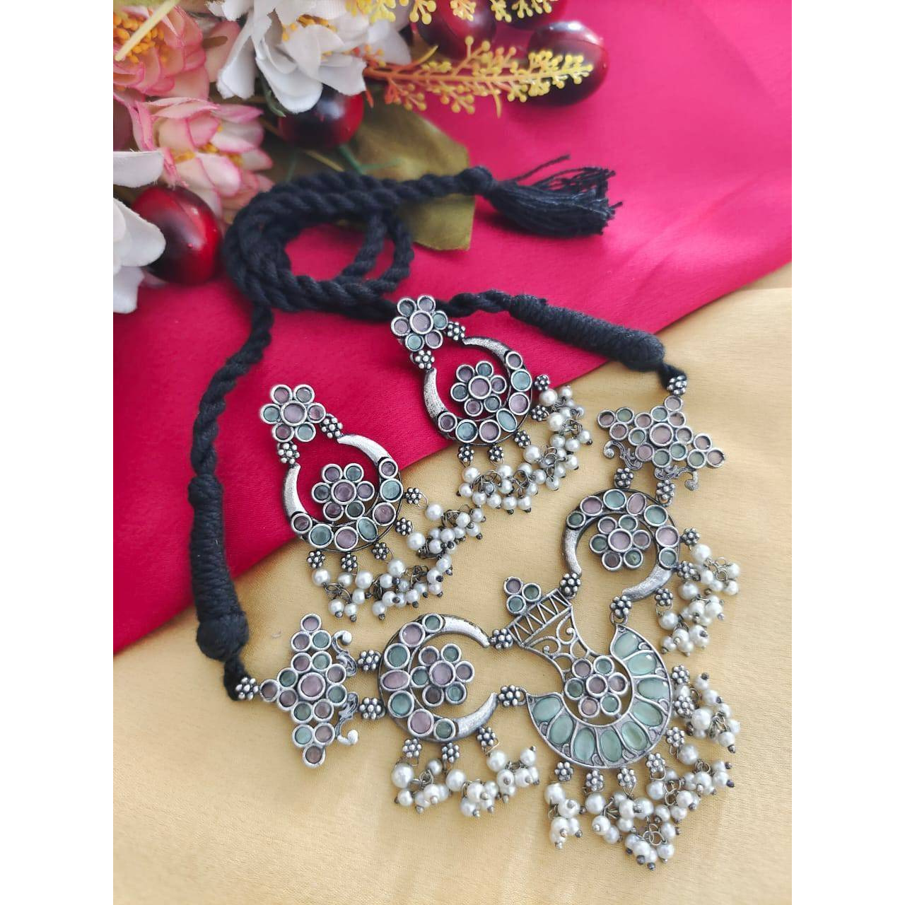 Delve into the world of finely crafted classics that powerfully capture the beauty of modern Indian craftsmanship. This elegant pair of oxidised silver plated earrings and maangtikka dressed up with tinkling pearl hangings and delicate filigree & peacock details, is one of our personal favourites. These earrings make effortless addition to your white hued attires, be it indian or western. A funky pair that can be used practically everyday and with various outfits and will definitely add to your