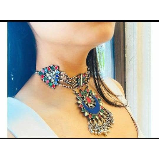 This Afghani Choker Necklace is crafted in oxidized silver that is a perfect amalgamation of beautiful multi-color enamel work and perky ghungroos that will lace your collar to give you a rich and vibrant look. Style this up for a high-statement boho look.